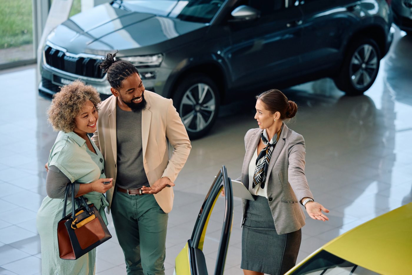 A couple talking with a salesperson in a dealership showroom, the start of a relationship that continues through service and ownership